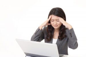 頭痛の辛い症状で仕事が進まずに悩む女性